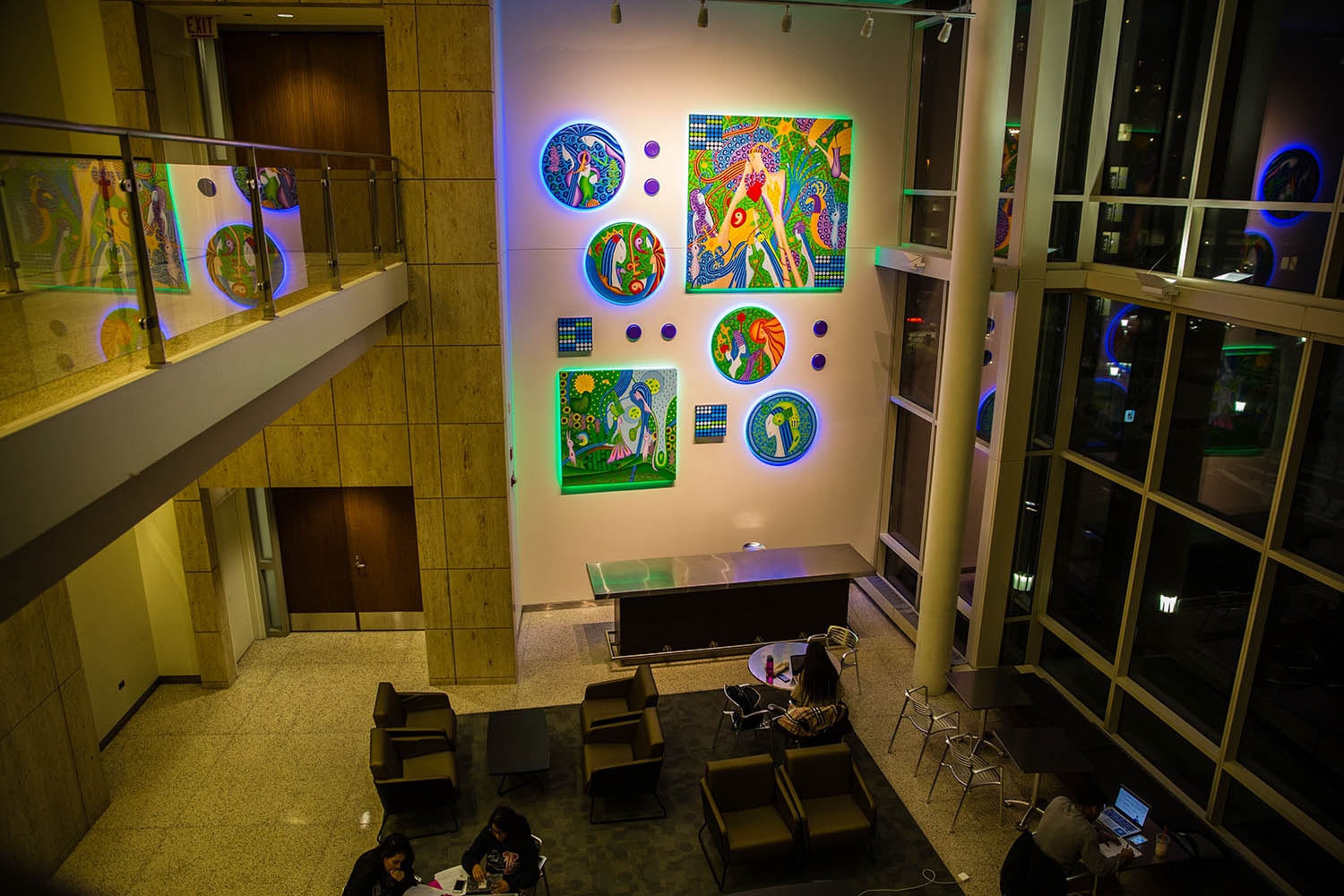 Biological Domains installation view with illuminated paintings on a gallery wall