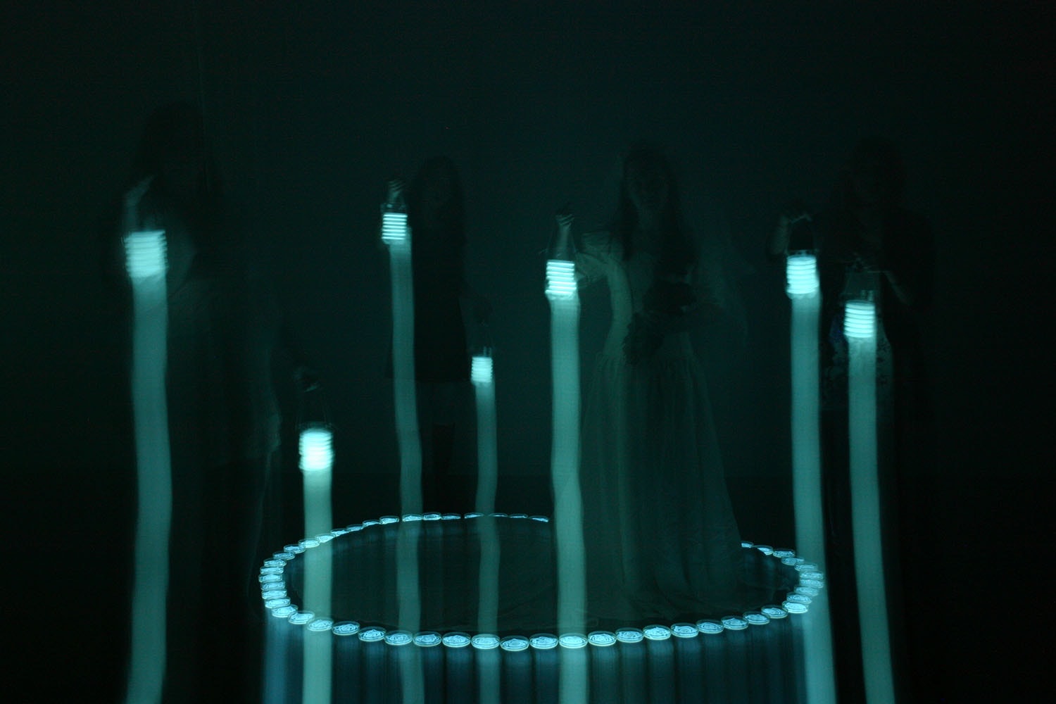 Bride Floating on Light, luminous cyan lights in a dark installation setting