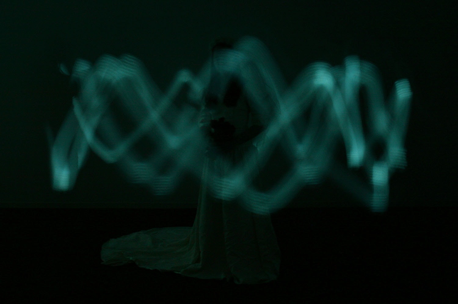 Swirl of Light Around the Bride, blurred figures illuminated by teal green light